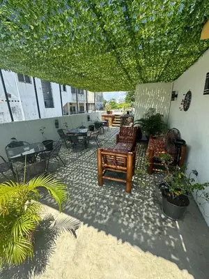 acovered patio with chairs and tables and plants at El Conde De Atrini in Santo Domingo