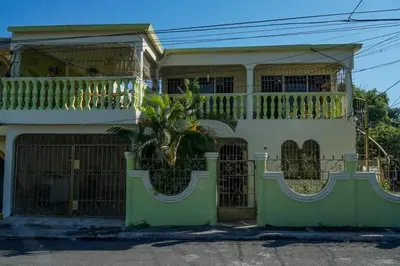 a house with a palm tree in front of it at Apartamento en la Romana 2 días en adelante in La Romana