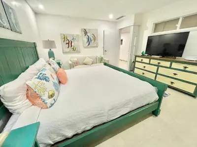 a bedroom with a large bed and a dresser with a television at 2 Bedroom At The Marbella Towers Beachfront in Juan Pedro