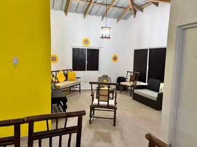 a living room with chairs and tables and a yellow wall at Sunflower village villa girasoles in Jarabacoa