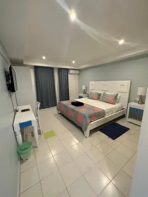 a bedroom with a bed and a desk and a television at Noe Hotel Punta Cana in Punta Cana