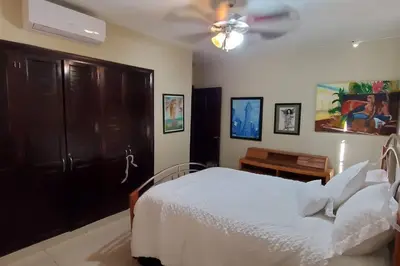 a bedroom with a white bed and a ceiling fan at Dominican Art 2 Bedroom condo El Cortecito in Punta Cana