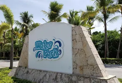 a sign on a wall with palm trees in the background at Dominican Art 2 Bedroom condo El Cortecito in Punta Cana