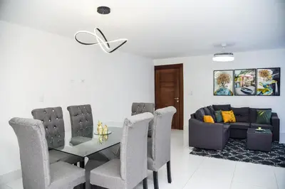 a dining room with a table and chairs and a couch at Torre Real VI in Santiago de los Caballeros