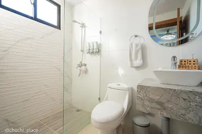 a white bathroom with a toilet and a sink at Chuchi Place in Santiago de los Caballeros