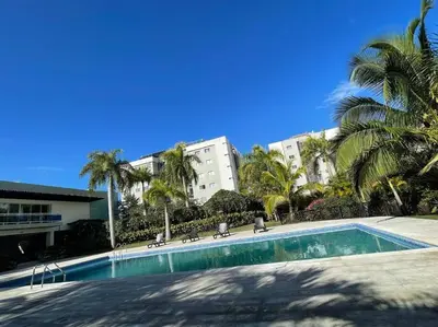 a swimming pool in front of a building with palm trees at Mountain View Cibao in Santiago de los Caballeros
