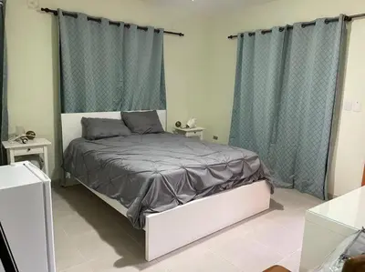 a bedroom with a bed with gray sheets and curtains at Villa Zarina - Polo Barahona in Polo