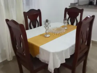 a dining room table with a white tablecloth and four chairs at Departamento Rosa in Santo Domingo