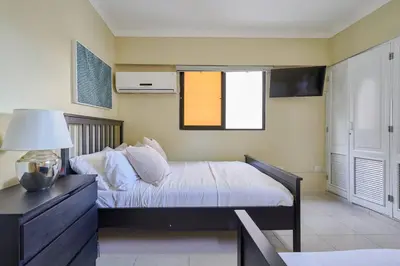 a bedroom with a bed and a table with a lamp at Escape Penthouse near Blue Mall - 4BR with Private Rooftop & City Views in Santo Domingo