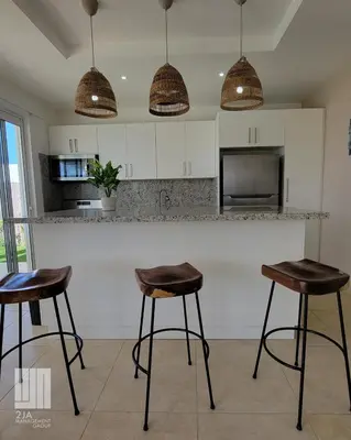 a kitchen with two bar stools in front of a counter at 2JA Management Group - SOV Properties in Sosúa