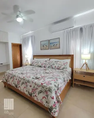 a bedroom with a bed with a floral bedspread and two lamps at 2JA Management Group - SOV Properties in Sosúa