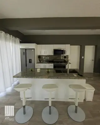 a kitchen with a counter and four bar stools at 2JA Management Group - SOV Properties in Sosúa