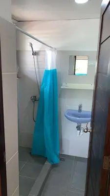 a bathroom with a blue shower curtain and a sink at Hotel Checo Sosúa in Sosúa