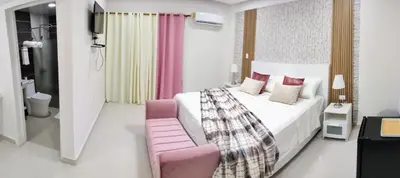 a bedroom with a bed and a pink chair at Hotel el barco in Azua de Compostela