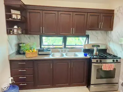 a kitchen with wooden cabinets and a stove and sink at Bright & Modern Apartment in Puerto Plata, Secure, and Central! in San Felipe de Puerto Plata