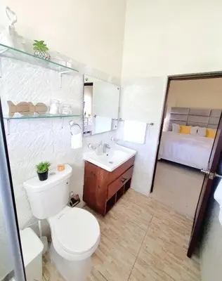 a bathroom with a toilet and a sink and a bed at Bright & Modern Apartment in Puerto Plata, Secure, and Central! in San Felipe de Puerto Plata