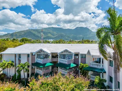 a row of houses with palm trees and mountains in the background at Bright & Modern Apartment in Puerto Plata, Secure, and Central! in San Felipe de Puerto Plata