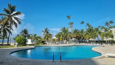 a pool at the resort with palm trees at Your Little Paradise - Juan Dolio in Juan Dolio