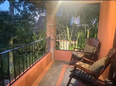a porch with two chairs and a balcony with trees at Escape Chalet at Pinar del Sol in Jarabacoa in Jarabacoa