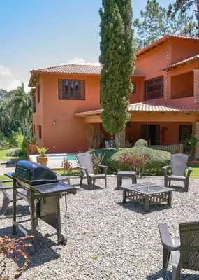 a group of chairs and tables in front of a house at Escape Chalet at Pinar del Sol in Jarabacoa in Jarabacoa