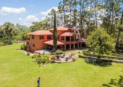 a man standing in front of a house at Escape Chalet at Pinar del Sol in Jarabacoa in Jarabacoa