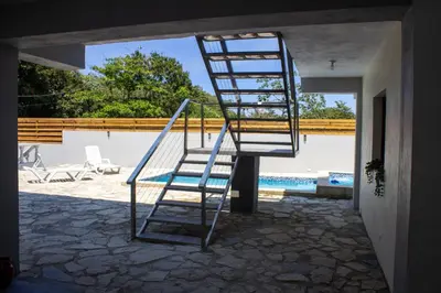 a ladder sitting outside of a house with a pool at Villa Mónaco Jarabacoa RD in Jarabacoa