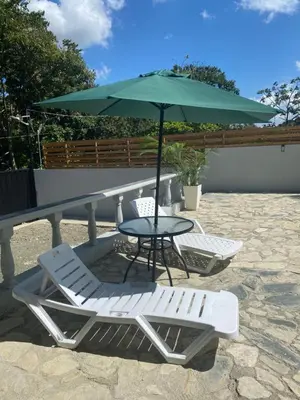 a table and two chairs and a table with an umbrella at Villa Mónaco Jarabacoa RD in Jarabacoa