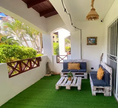 a porch with green carpet and blue chairs and a table at Xarraca, excepcional apartamento in Bayahibe