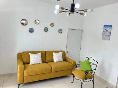 a living room with a yellow couch and a chair at Complejo girasol in Santo Domingo