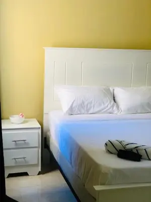 a bedroom with a white bed and a night stand at J&W apartment in San Felipe de Puerto Plata