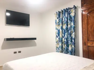 a bedroom with a bed and a tv on a wall at Ocean View Apart. In Down town in San Felipe de Puerto Plata