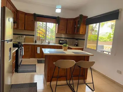 a kitchen with wooden cabinets and a island with two stools at Casa Canephora in Las Galeras