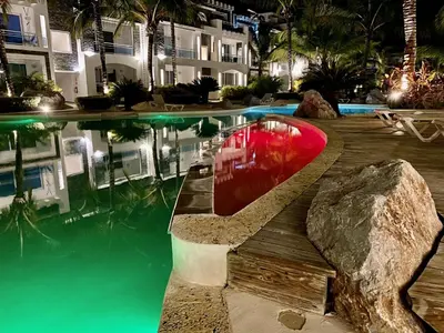 a pool at a hotel with a red boat in the water at Apartment in Estrella, Dominicus-Bayahibe in La Laguna