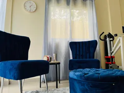 two blue chairs sitting next to a window with a clock at Casa Bonita Pimentel in Pimentel