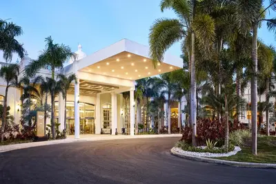 a building with palm trees in front of a street at Riu Palace Bavaro - All Inclusive in Punta Cana