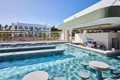 a pool at a hotel with tables and chairs at Riu Palace Bavaro - All Inclusive in Punta Cana