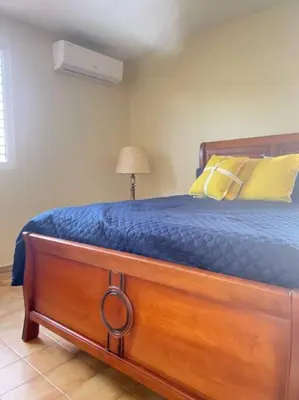 a bedroom with a bed with a blue blanket and yellow pillows at LA CASA DE MAMA LUZ in San Felipe de Puerto Plata