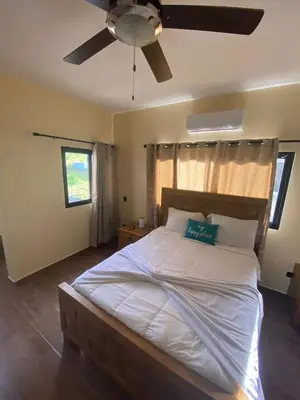 a bedroom with a large bed with a ceiling fan at VillaLunaCaridad in Jarabacoa