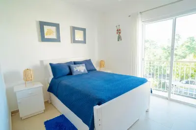a white bedroom with a blue bed and a window at Apartment in Dominicus in Bayahibe