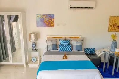 a bedroom with a bed with blue and white pillows at Royal Terrace IV (King) in San Felipe de Puerto Plata
