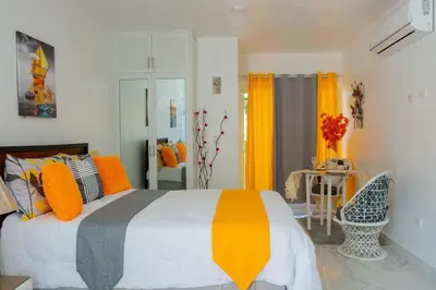a bedroom with a bed with orange and gray pillows at Royal Terrace Apto. II (Princess) in San Felipe de Puerto Plata